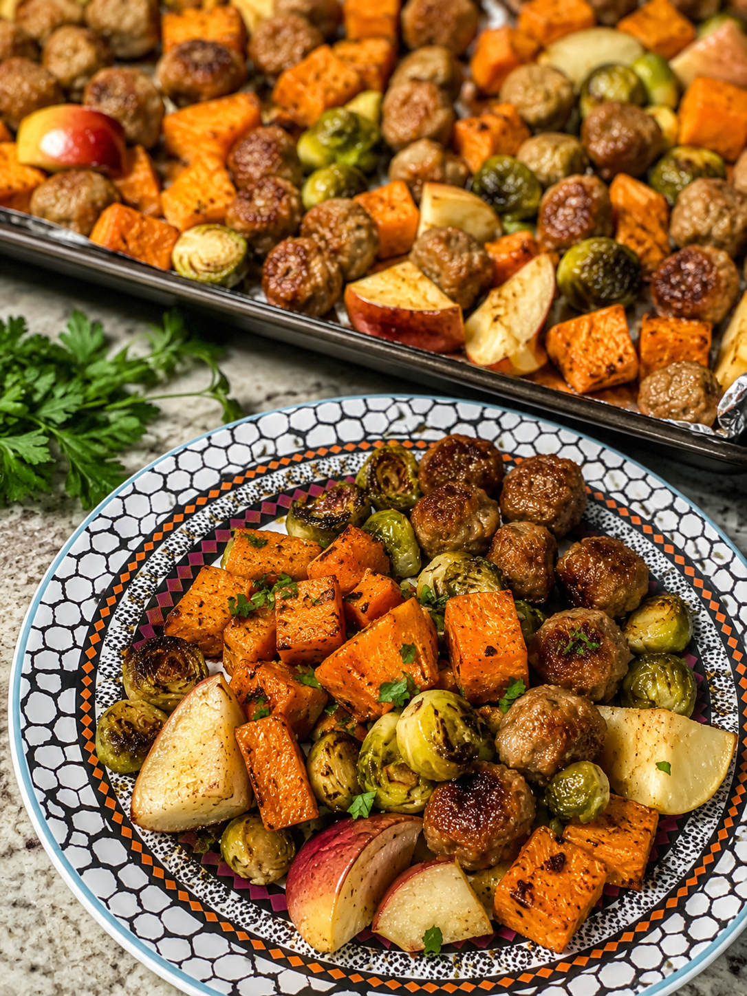 Roasted sausage, sweet potato, Brussels sprouts, and apples plated and on a sheet pan
